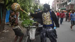 Seorang pria berkostum dewa kematian Yamaraj saat mengimbau warga yang tidak memakai masker di tengah lockdown di Kolkata, India (24/4/2020). Aksinya tersebut sebagai langkah mendukung aturan lockdown India guna mencegah penyebaran wabah pandemi Covid-19 di Kolkata. (AFP/Dibyangshu Sarkar)