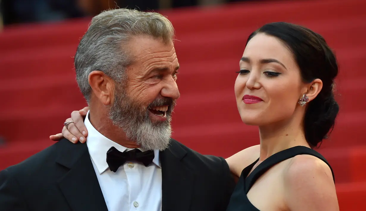 Aktor senior Mel Gibson tampak menatap sang kekasih, Rosalind Ross saat berpose di acara penutupan Festival Film Cannes, Prancis, 22 Mei 2016.  Seperti yang diketahui, usia Mel Gibson dan kekasih cantiknya terpaut 35 tahun. (A LOIC VENANCE/AFP)