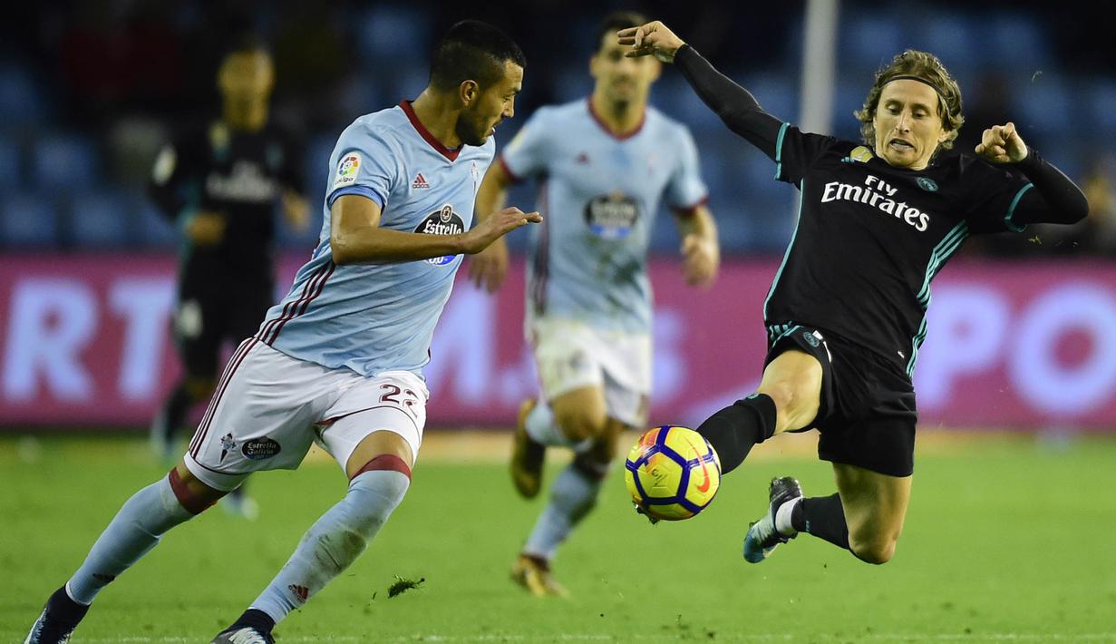 Gelandang Real Madrid, Luka Modric, berebut bola dengan bek Celta Vigo, Gustavo Cabral, pada laga La Liga Spanyol di Stadion Balaidos, Vigo, Minggu (7/1/2018). Kedua klub bermain imbang 2-2. (AFP/Miguel Riopa)