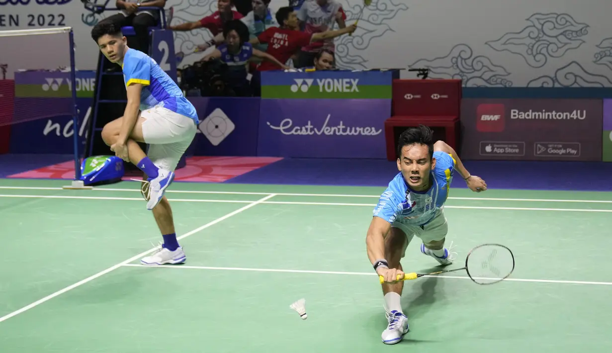 Ganda putra Indonesia Pramudya Kusumawardana (kanan) mencoba mengembalikan kok saat rekannya Yeremia Rambitan memegang lututnya yang cedera pada perempat final Indonesia Open 2022 melawan pasangan Malaysia Aaron Chia/Soh Wooi Yik di Istora Senayan, Jakarta, Jumat (17/6/2022). (AP Photo/Dita Alangkara)