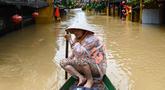 Seorang perempuan mendayung perahu di jalanan yang terendam banjir setelah hujan deras di Hoi An, Vietnam, Kamis 30 Oktober 2025. Hujan deras dengan intensitas tertinggi sepanjang sejarah memicu banjir besar di Vietnam bagian tengah. (NHAC NGUYEN/AFP)
