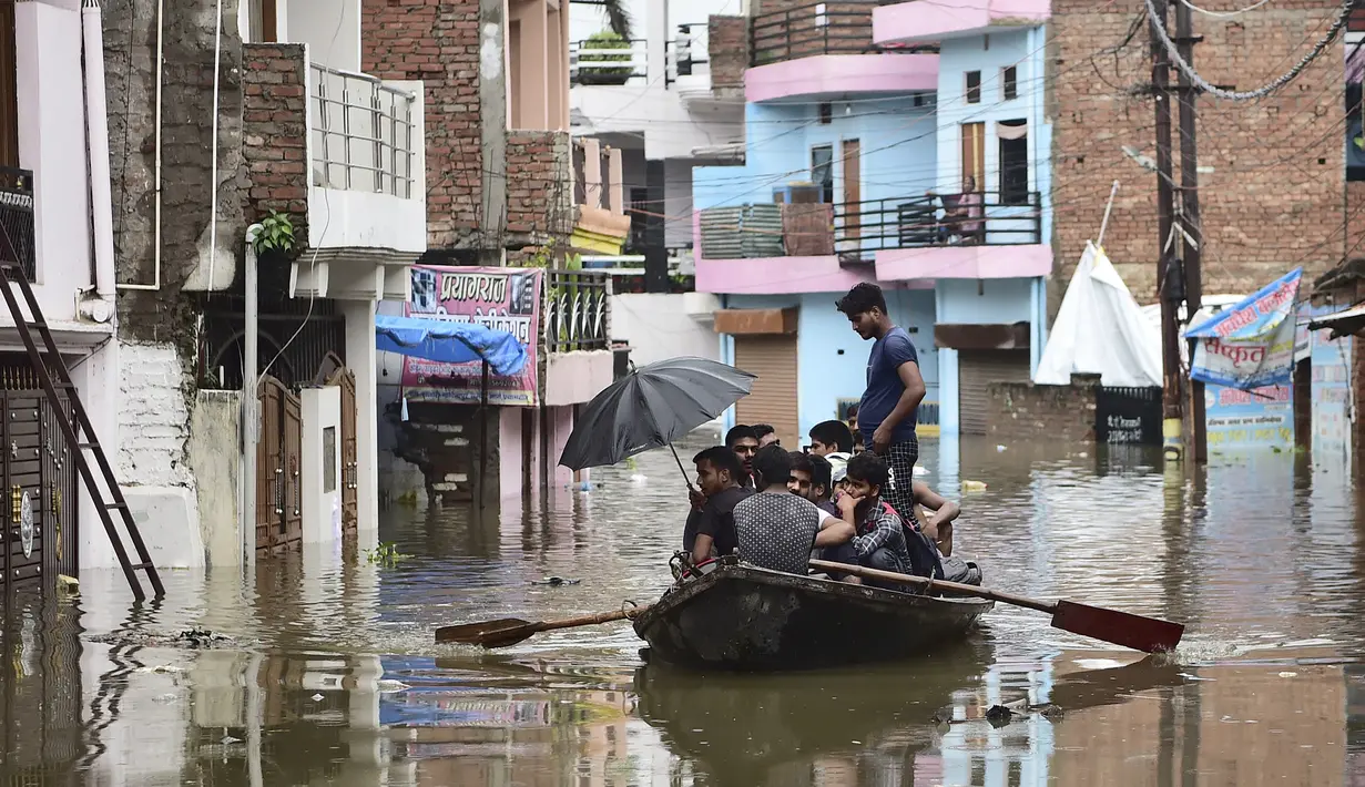 Warga menaiki perahu saat melintasi jalan yang terendam banjir di Chhota Baghara, Allahabad, India, Rabu (11/8/2021). Hujan lebat menyebabkan banjir di Allahabad. (SANJAY KANOJIA/AFP)