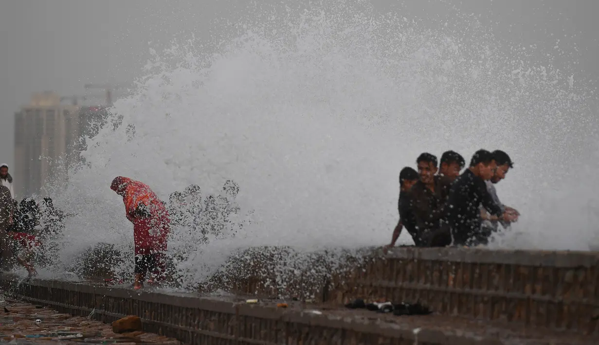 Orang-orang menikmati percikan air ombak selama musim panas di laut Arab di Karachi, Pakistan (14/6/2019). Memasuki musim panas, warga Pakistan ramai-ramai mendinginkan tubuhnya di laut. (AFP Photo/Asif Hassan)