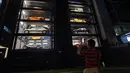 Seorang pria mengambil gambar vending machine atau mesin penjual otomatis berisi mobil-mobil mewah di gedung Autobahn Motors, Singapura, Kamis (18/5). Vending machine berbentuk bangunan bertingkat itu dapat menampung hingga 60 mobil. (ROSLAN RAHMAN/AFP)