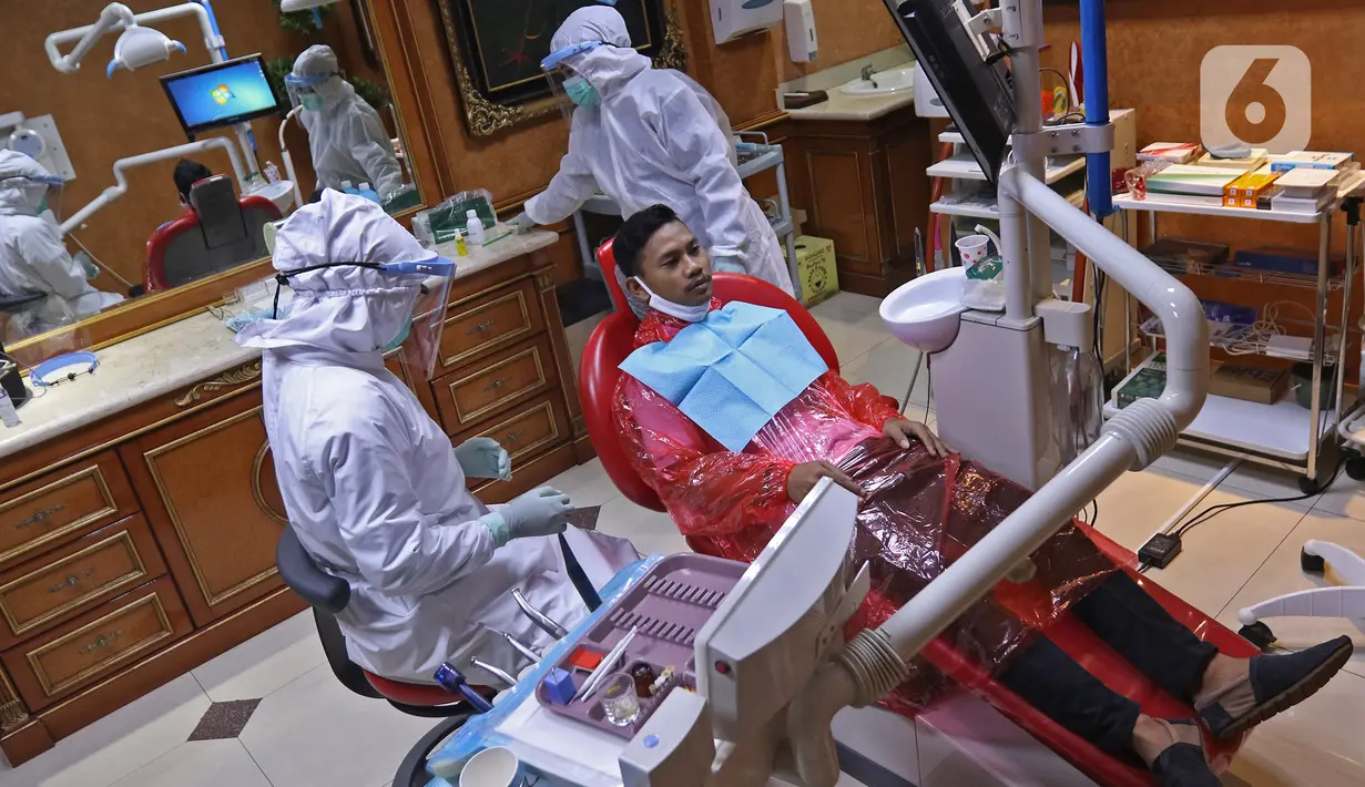 drg. Ayusha (kiri) mengenakan alat perlindungan diri (APD) saat memeriksa pasien di salah satu klinik di kawasan Pulo Gadung, Jakarta, Rabu (22/4/2020). Penggunaan APD dilakukan sebagai SOP pemeriksaan gigi saat pandemi serta mengantisipasi penularan COVID-19. (Liputan6.com/Herman Zakharia)