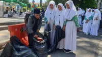 Para santri tengah memunguti sampah yang berserakan di halangan Otista, ALun-alun Garut, selepas perayaan Hari Santri Nasional (HSN) 2022 di Garut. (Liputan6.com/Jayadi Supriadin)