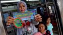 Seorang wanita menunujukkan stiker informasi pengaduan kekerasan di sekitar Stasiun Tanah Abang, Jakarta, Kamis (21/12). Stiker ini bertuliskan informasi tentang pengaduan ketika terjadi kekerasan pada wanita dan anak. (Liputan6.com/JohanTallo)