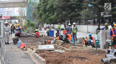 Pekerja menyelesaikan jalur pedestrian di Jalan Sudirman, Jakarta, Senin (2/7). Perbaikan jalur pedestrian di sepanjang koridor Jalan Sudirman menjadi porsi pekerjaan PT MRT Jakarta, ditargetkan selesai pada 31 Juli 2018. (Liputan6.com/Arya Manggala)