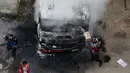 Petugas pemadam kebakaran berusaha memadamkan api dari truk yang dibakar para demonstran saat menggelar aksinya di Caracas, Venezuela (24/4). (AP Photo/Fernando Llano)