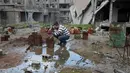 Mohamed Ataya menyiram tanaman yang ditanam disebuah kaleng bekas di atap bangunan yang rusak di wilayah Ghouta timur di ibukota Damaskus, Suriah (3/3). Sebelumnya, Abu Maher adalah seorang pemain sepak bola profesional. (AFP/Amer Almohibany)