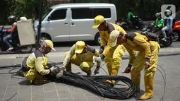 Petugas Bina Marga merapikan kabel optik yang baru saja dipotong di sepanjang jalan kawasan Kemang, Jakarta, Kamis (24/10/2019). Pemotongan kabel optik tersebut untuk menertibkan instalasi kabel yang semrawut serta mengganggu ketertiban umum di kawasan Kemang. (Liputan6.com/Immanuel Antonius)