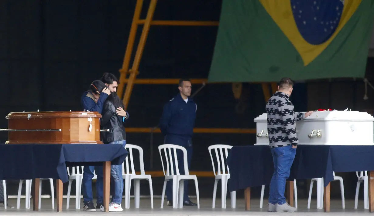 Kerabat korban kecelakaan pesawat Voepass berduka di samping peti mati mereka dalam sebuah misa di pangkalan udara Sao Paulo di Guarulhos, Brasil, Selasa (13/8/2024). (Miguel SCHINCARIOL / AFP)