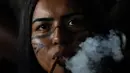 Seorang wanita Pribumi Pataxo merokok pipa tradisional selama upacara yang disebut Pertemuan Masyarakat Pertama di Kamp Adat Tanah Bebas tahunan ke-18 di Brasilia, Brasil (8/4/2022). Acara digelar selama 10 hari. (AP Photo/Eraldo Peres)