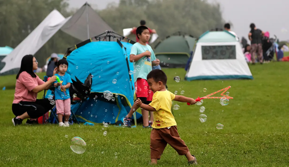 Seorang anak bermain gelembung saat orang-orang berkemah di gunung yang indah di Yanqing, Beijing pada 30 Agustus 2020. China memiliki lebih dari 200 orang yang dirawat di RS karena COVID-19, dengan lebih dari 300 lainnya diisolasi setelah dites positif terkena virus tanpa gejala. (AP/Andy Wong)