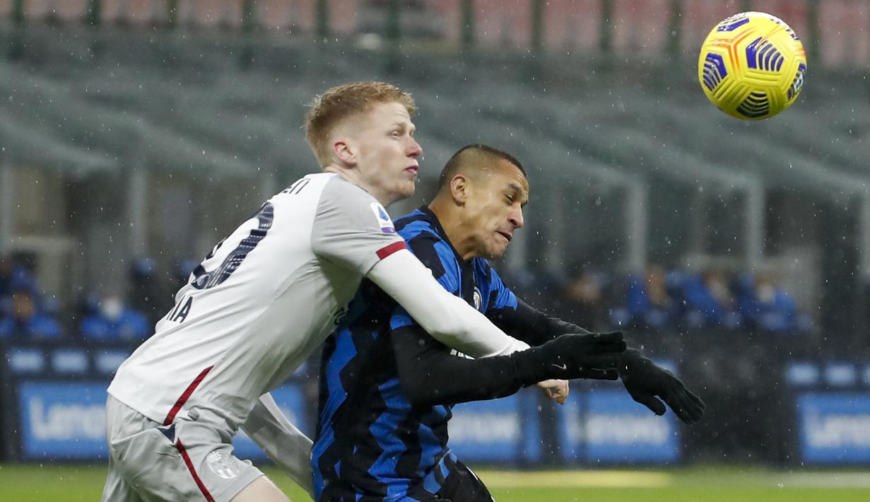 Striker Inter Milan, Alexis Sanchez (kanan), berebut bola dengan gelandang Bologna, Jerdy Schouten dalam laga lanjutan Liga Italia Serie A pekan ke-9 di San Siro Stadium, Sabtu (5/12/2020). Inter milan mengalahkan Bologna 3-1. (AP/Antonio Calanni)