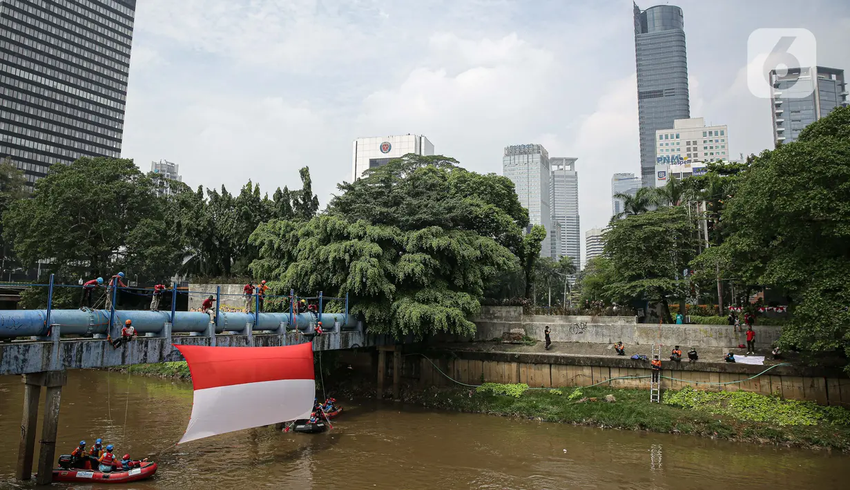Sejumlah relawan membentangkan bendera Merah Putih di aliran kali
Ciliwung di kawasan Sudirman, Jakarta, Minggu (22/8/2021). Pembentangan atau pengibaran bendera Merah Putih tersebut dilaksanakan untuk memperingati HUT ke-76 RI. (Liputan6.com/Faizal Fanani)