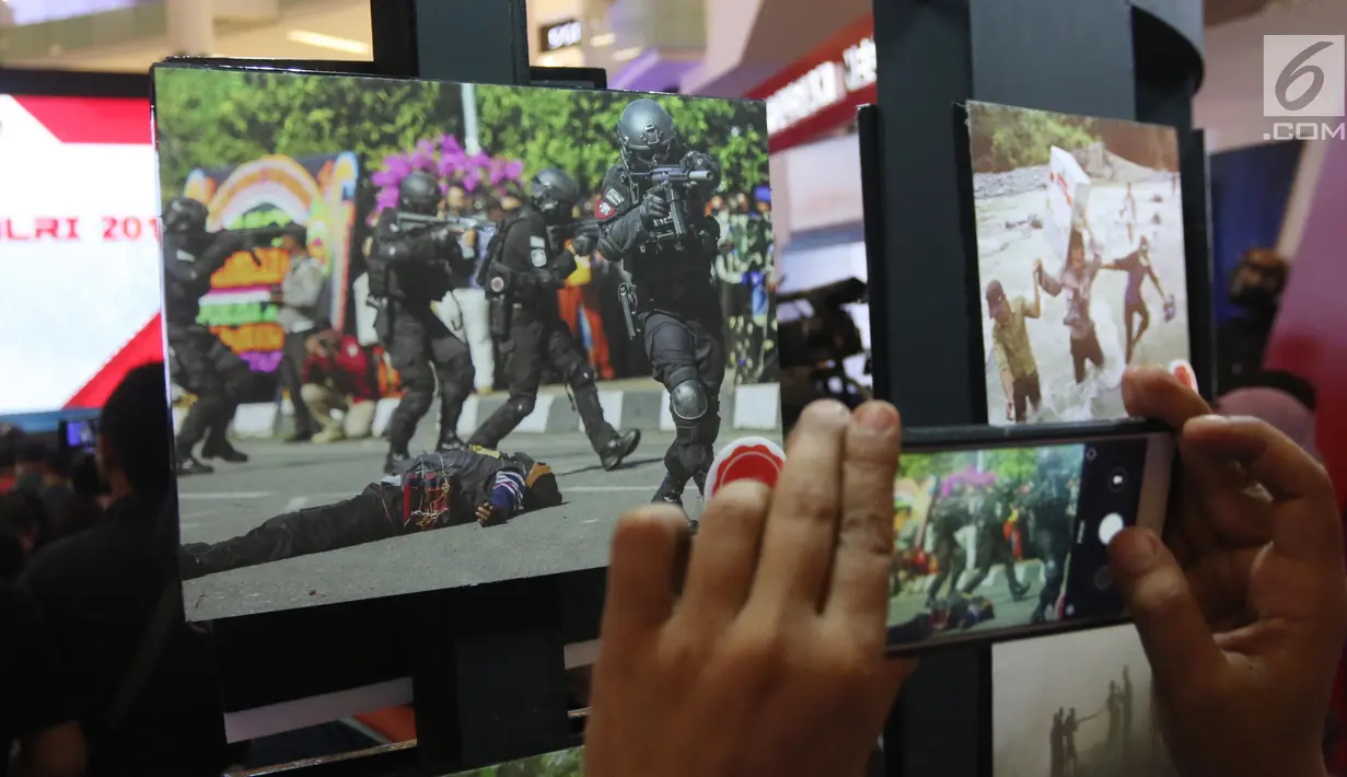 Pengunjung menggunakan ponsel mengambil gambar karya-karya foto pemenang Anugerah Jurnalistik Polri 2018 di Gandaria City, Jakarta, Rabu (18/7). Anugerah Jurnalistik 2018 ini bertema Bersama Polri Wujudkan Pilkada Damai 2018. (Liputan6.com/Arya Manggala)