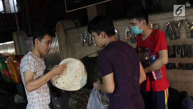 Pencari suaka berbagi makanan di atas trotoar depan Masjid Ar-Rayan, Jalan Kebon Sirih, Jakarta, Jumat (5/7/2019). Para pencari suaka dari sejumlah negara berkonflik berharap UNHCR bisa segera memberikan jaminan perlindungan bagi mereka. (Liputan6.com/Helmi Fithriansyah)