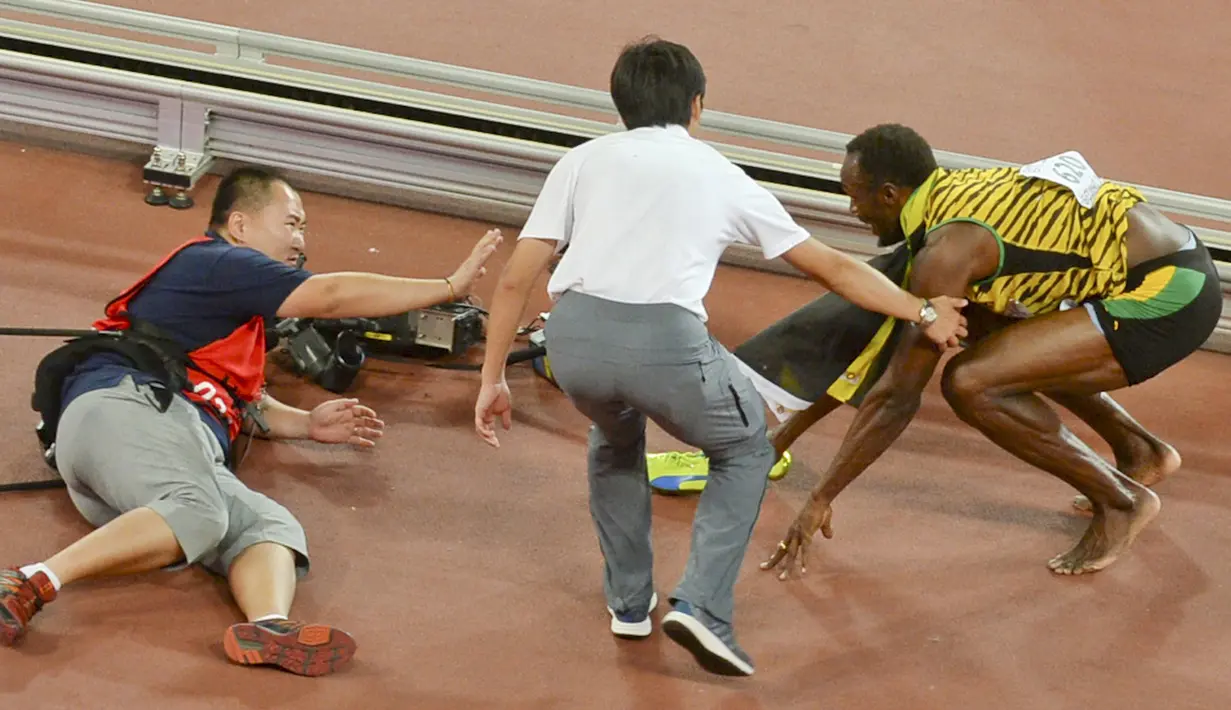 Pelari Jamaika, Usain Bolt langsung berdiri usai tertabrak kameramen yang mengendarai skuter saat dirinya melakukan selebrasi kemenangan meraih medali emas di nomor 200 meter di Kejuaran Dunia Atletik di Beijing, Kamis (27/8). (REUTERS/Stringer CHINA OUT)