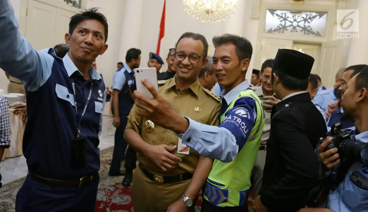 Pegawai Transjakarta berswafoto bersama Gubernur DKI Jakarta Anies Baswedan di Balai Kota DKI Jakarta, Selasa (20/3). Anies mengaku senang dengan capaian Transjakarta yang tembus 500 ribu penumpang per hari. (Liputan6.com/Pool/Dadang WS)