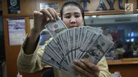 Teller tengah menghitung mata uang dolar di penukaran uang di Jakarta, Junat (23/11). Nilai tukar dolar AS terpantau terus melemah terhadap rupiah hingga ke level Rp 14.504. (Liputan6.com/Angga Yuniar)