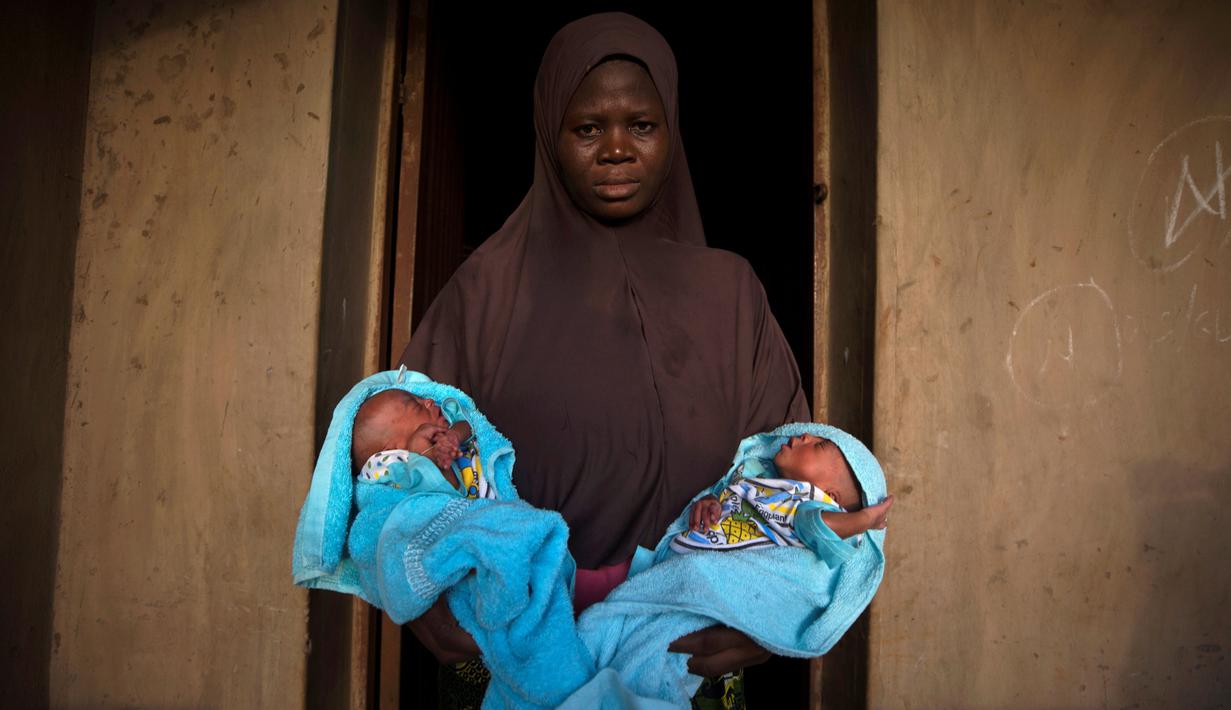 Seorang wanita muslim menggendong saudara laki-laki kembarnya yang berumur 4 hari di depan pintu rumahnya di Igbo Ora, Negara Bagian Oyo, Nigeria pada 3 April 2019.  Igbo Ora, sebuah wilayah di bagian barat daya Nigeria ini terkenal dengan anak-anaknya yang terlahir kembar. (REUTERS/Afolabi Sotunde)