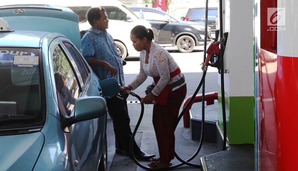 Petugas dengan pakaian adat mengisi bahan bakar minyak (BBM) ke sebuah taksi di SPBU, Bali, Rabu (10/10). Petugas SPBU mengenakan pakaian adat Bali untuk menyambut pertemuan tahunan IMF dan Bank Dunia. (Liputan6.com/Angga Yuniar)