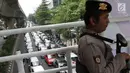 Polisi berjaga di atas jembatan penyebrangan saat berlangsungnya unjuk rasa pengemudi taksi online yang tergabung Aliansi Nasional Driver Online Indonesia di depan Kantor GO-JEK Indonesia, Selasa (25/9). (Liputan6.com/Helmi Fithriansyah)
