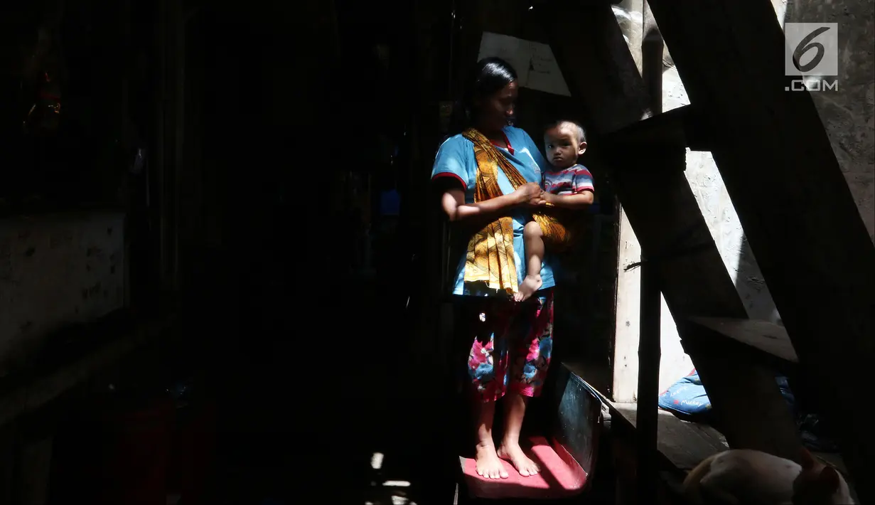 Seorang ibu menggendong anaknya yang masih kecil di kawasan Kapuk, Jakarta, Senin (26/3). Gubernur DKI Jakarta Anies Baswedan mengatakan 50 persen penduduk Jakarta tidak memiliki rumah sendiri. (Liputan6.com/JohanTallo)