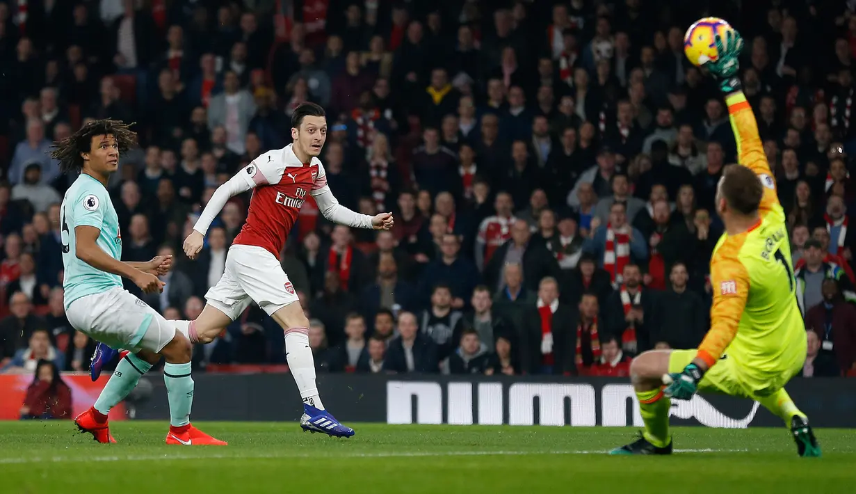 Kiper Bournemouth Artur Boruc gagal menghalau bola dari pemain Arsenal, Mesut Ozil yang menjebol gawangnya pada laga lanjutan Liga Inggris, 2018-19 pekan ke-28 di Emirates Stadium, Rabu (27/2). Arsenal menang dengan skor telak 5-1. (Ian KINGTON/AFP)
