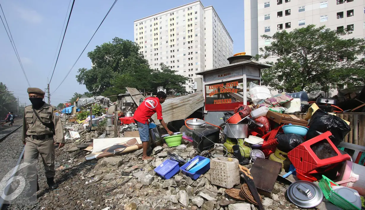 Warga merapihkan barang miliknya saat alat berat merobohkan bangunan di kawasam Rawajati, Jakarta, Kamis (1/9). Penertiban tersebut menyebabkan warga terpaksa menyelamatkan barang berharga mereka ke tepi rel kereta api. (Liputan6.com/Immanuel Antonius)