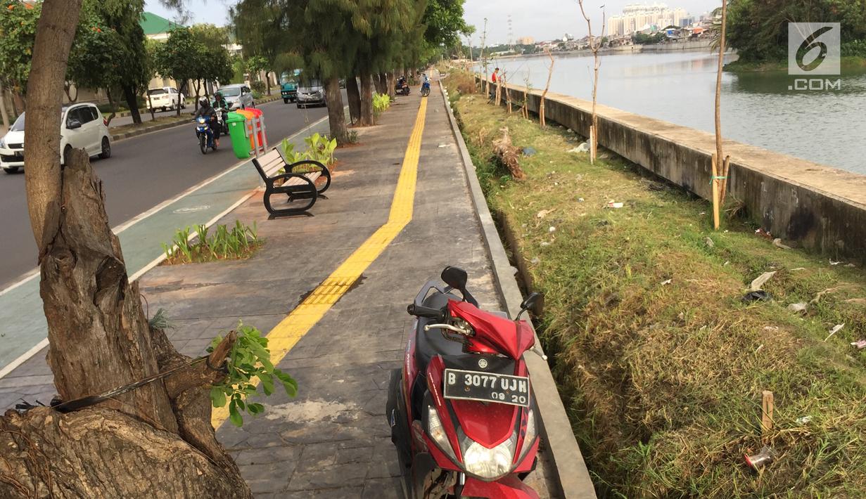 Pengendara sepeda motor memarkirkan kendaraannya di trotoar Danau Sunter, Jakarta, Jumat (19/1). Hal ini dikerenakan kurangnya kesadaran warga yang akhirnya merugikan pengguna trotoar semestinya, yaitu pejalan kaki. (Liputan6.com/Immanuel Antonius)