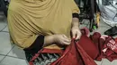 Siti Zahro (44) menyelesaikan pembuatan celemek berbahan tas bansos Covid-19 di industri jahit rumahan KG-Lupe Fashion, Salemba, Jakarta, Senin (16/11/2020). Dalam sehari Siti mampu memproduksi tiga buah celemek. (merdeka.com/Iqbal S. Nugroho)