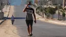 Seorang pria Palestina dengan mengenakan masker berjalan saat pemberlakukan lockdown selama 48 jam di Jalur Gaza, Selasa (25/8/2020). Lockdown dan jam malam diberlakukan di wilayah jalur Gaza menyusul terkonfirmasinya kasus Covid-19 pertamanya di sebuah kamp pengungsian. (AP Photo/Hatem Moussa)