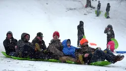 Sekelompok warga meluncur menuruni bukit salju di Dorothea Dix Park di Raleigh, Carolina Utara, Amerika Serikat (AS), Rabu (17/1). Gubernur Carolina Utara Roy Cooper mengumumkan keadaan darurat jelang badai musim dingin. (Lance King/Getty Images/AFP)