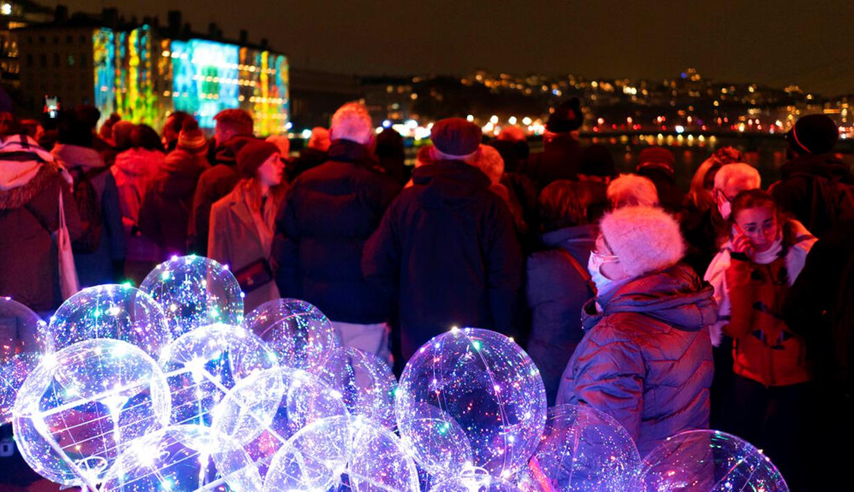 Orang-orang menghadiri pertunjukan cahaya malam di Lyon, Prancis, 8 Desember 2022. Jutaan orang diperkirakan akan menyaksikan acara Festival Cahaya selama empat hari di kota tersebut. (AP Photo/Laurent Cipriani)
