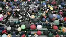 Penonton memegang payung saat turun hujan pada laga antara Richard Gasquet dan Kei Nishikori pada turnamen Prancis Terbuka 2016 di Roland Garros, (28/5/2016). (AFP/Philippe Lopez)