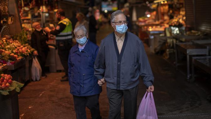 Sepasang suami istri berjalan di sebuah pasar di Barcelona, Spanyol, Rabu (29/4/2020). Pandemi virus corona COVID-19 mengakibatkan tingkat pengangguran Spanyol naik menjadi 14,4 persen pada kuartal pertama 2020. (AP Photo/Emilio Morenatti)