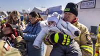 Seorang petugas pemadam kebakaran Polandia menggendong bayi di perbatasan Medyka pada 17 Maret 2022. Lebih dari tiga juta warga Ukraina telah melarikan diri melintasi perbatasan, kebanyakan perempuan dan anak-anak, menurut ke PBB. (Wojtek RADWANSKI/AFP)