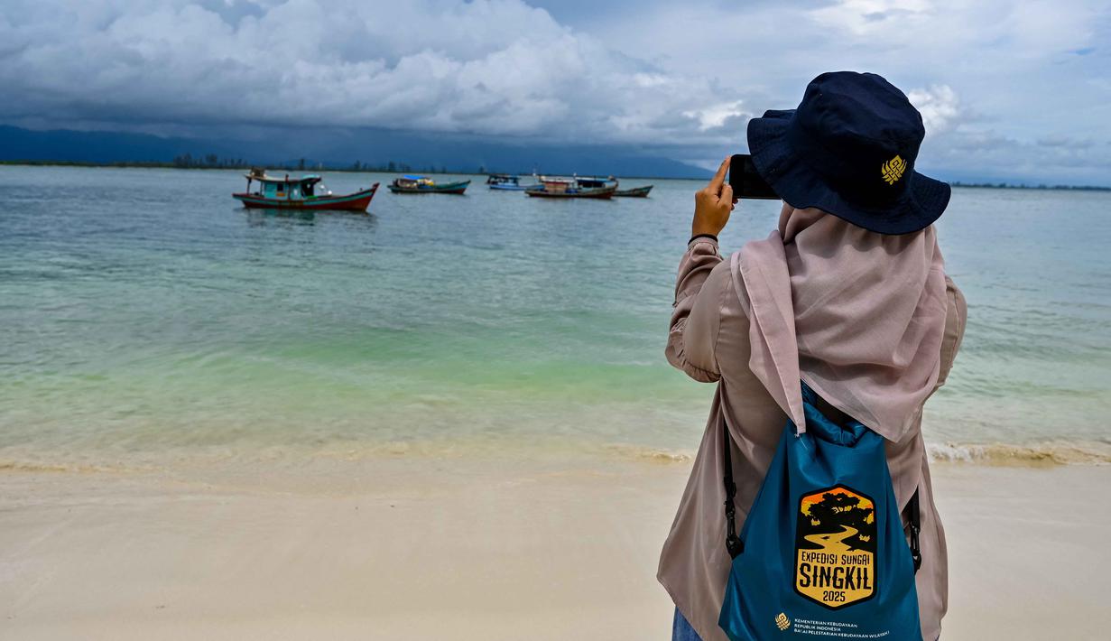 Pulau ini terletak di Desa Pulau Baguk, kecamatan Pulau Banyak, Aceh. Tampak dalam foto seorang wanita mengambil foto di Pulau Panjang, yang pernah menjadi objek sengketa batas pulau antara Aceh dan Sumatra Utara, di Singkil, Provinsi Aceh bagian selatan, pada Rabu 12 November 2025. (CHAIDEER MAHYUDDIN/AFP)