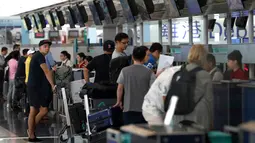 Calon penumpang pesawat memeriksa penerbangan mereka di bandara Hong Kong, Rabu (14/8/2019). Bandara Hong Kong kembali membuka penerbangan keberangkatan pada Rabu pagi setelah sempat lumpuh selama dua hari akibat demonstran menduduki salah satu bandara tersibuk di dunia tersebut. (AP/Vincent Thian)