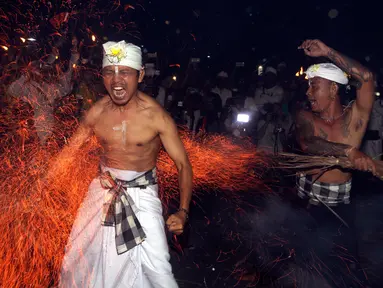 Seorang pria Bali dipukul dengan daun kelapa yang menyala saat ritual Lukat Gni di Klungkung, Bali (16/3). Tradisi lukat gni ini berasal dari dua kata yakni ‘lukat’ dan ‘gni’, malukat atau pembersihan, gni artinya api. (AP Photo / Firdia Lisnawati)