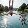 Para pemuda melompat ke Sungai Aare di Bern, Swiss, 21 Juni 2017. Selain panjang dan luas, Sungai Aare juga memiliki kedalaman mencapai 200 meter yang berlokasi dekat Meiringen. (Fabrice COFFRINI/AFP)
