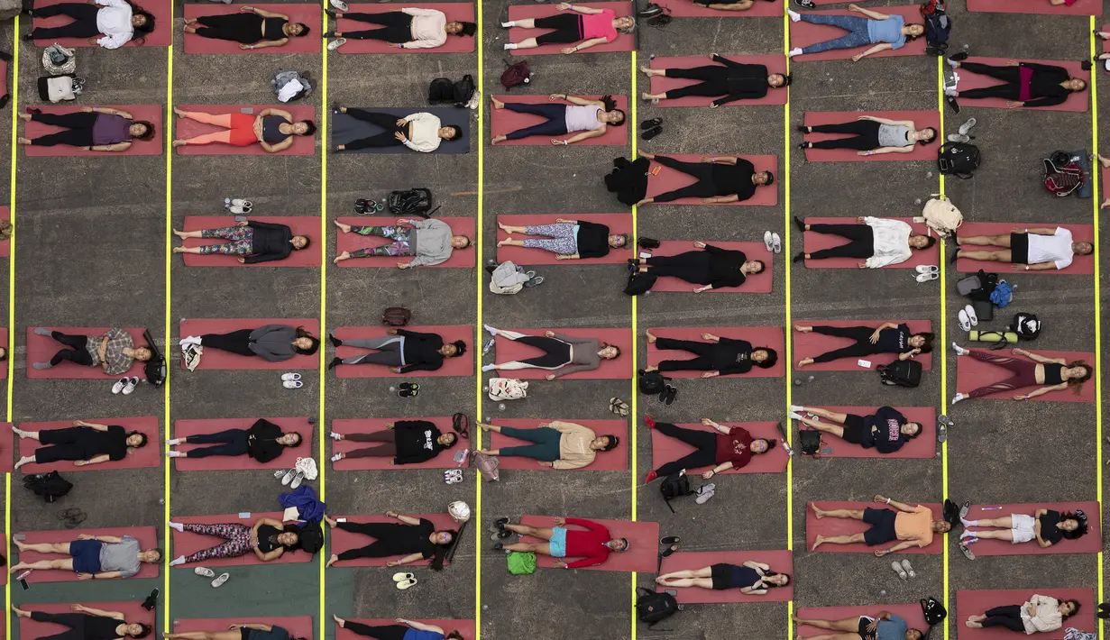 Selama dua puluh tahun terakhir, penyelenggara telah mengadakan acara yoga pada hari terpanjang dalam setahun, di salah satu persimpangan tersibuk di dunia, untuk mempromosikan kedamaian dan ketenangan. (AP Photo/Yuki Iwamura)
