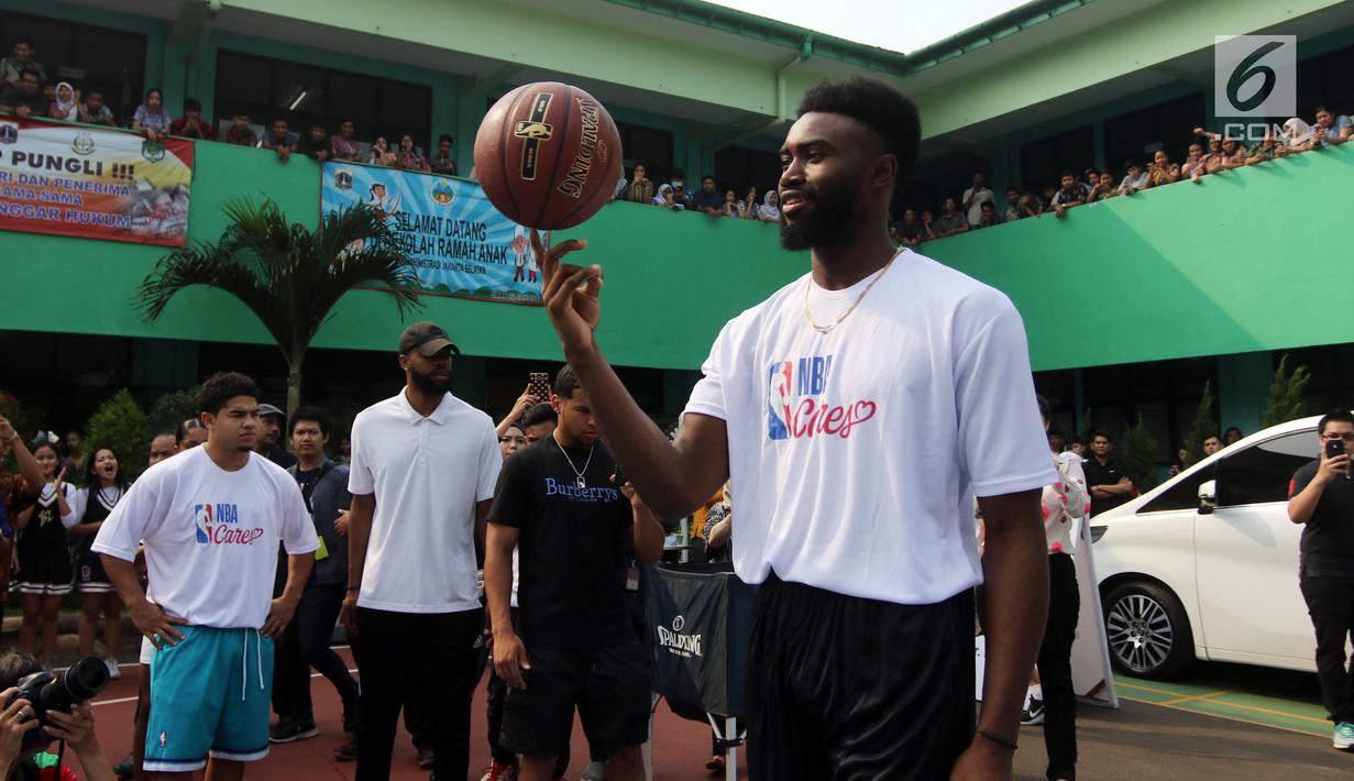 Pemain NBA dari Boston Celtics, Jaylen Brown menunjukkan kemampuannya memutar bola basket dengan satu jari saat memberi coaching clinics untuk siswa-siswi di SMAN 82 Jakarta, Kamis (26/7). (Liputan6.com/Arya Manggala)