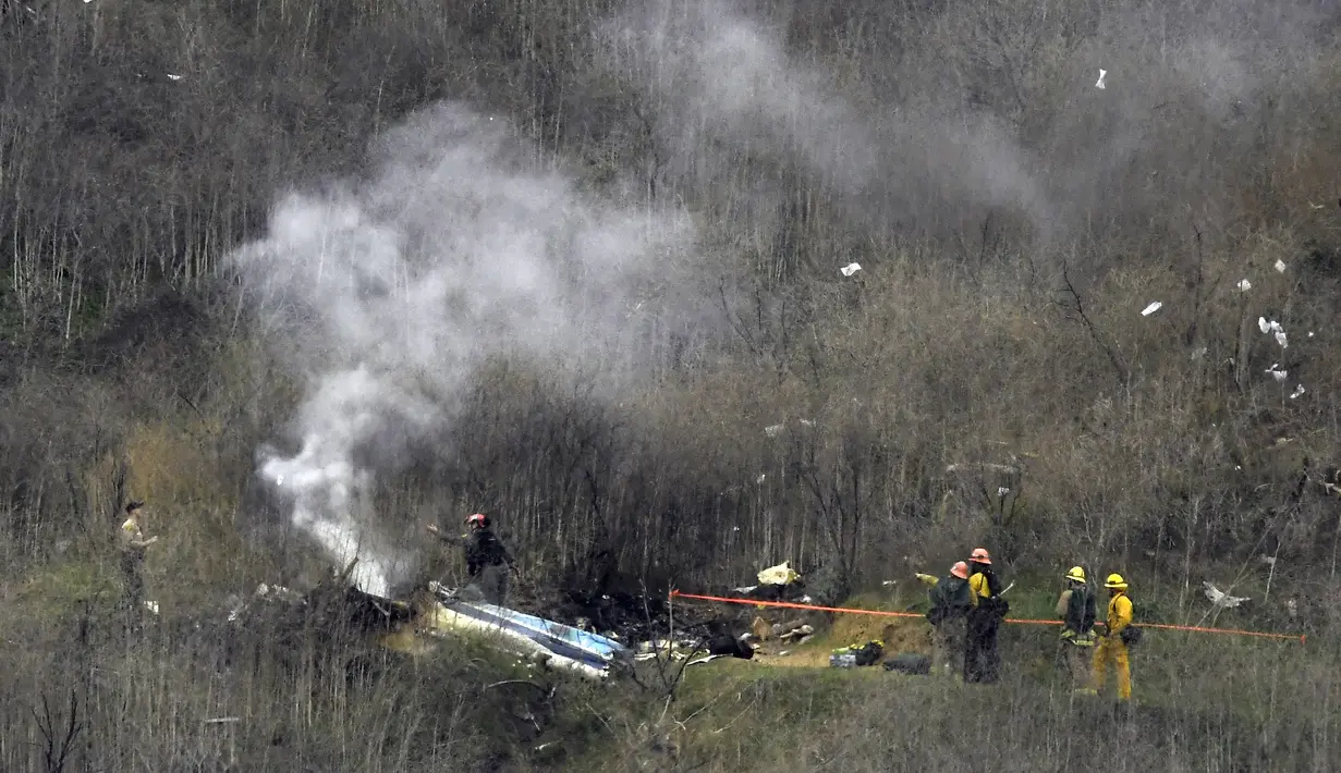 Sejumlah petugas berusaha mengevakuasi korban jatuhnya helikopter di Calabasas, California, Minggu (26/1/2020). Legenda NBA, Kobe Bryant, menjadi salah satu korban tewas pada kecelekaan helikopter berjenis Sikorsky S-76B itu. (AP/Mark J. Terrill)