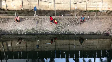 Sejumlah warga memancing ikan di kubangan yang berada di Jalan DI Panjaitan, Jatinegara, Jakarta, Selasa (16/6/2020). Meski telah dipagari, sejumlah warga tetap memancing ikan di lokasi yang merupakan saluran pembuangan tersebut. (Liputan6.com/Immanuel Antonius)