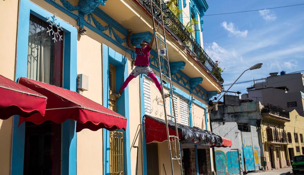 Seorang pria mengecat bagian balkon di Havana, Kuba (28/12). Kota ini terletak sekitar 144 kilometer di selatan-barat daya dari Key West, Florida.  (AP Photo / Desmond Boylan)