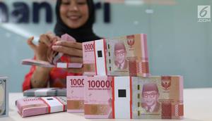 Teller tengah menghitung mata uang rupiah dan dolar di Bank Mandiri, Jakarta, Kamis (10/1). Nilai tukar rupiah terhadap dolar Amerika Serikat (AS) terus menguat di perdagangan pasar spot hari ini. Rupiah berada di zona hijau. (Liputan6.com/Angga Yuniar)