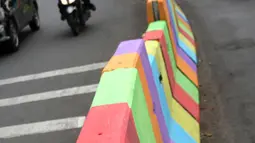 Pengendara motor melintasi di sisi pemisah jalan di Jalan Raya Ragunan sekitar Pasar Minggu, Jakarta, Selasa (24/7). Di kawasan ini pemisah jalan di cat warna warni sehingga terlihat lebih semarak. (Liputan6.com/Helmi Fithriansyah)